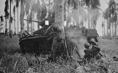 Black and white image of a tank and two soldiers in Buna.