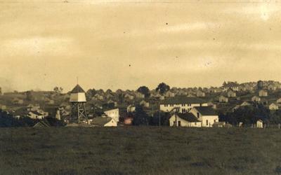 Landscape view of Buxton, Iowa, circa 1910. The photograph shows two water towers, a few two-story buildings, dozens of identical houses, along with streets of the town.