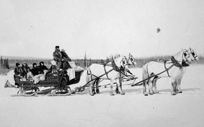 A team of horses pulls a U.S. Postal Service mail sled with postal carriers in Alaska.