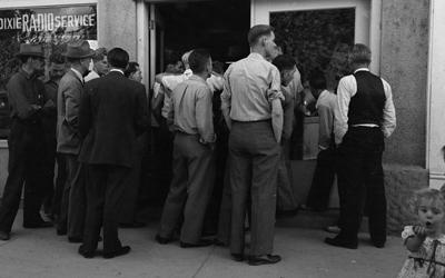 A crowd of men gather outside a radio shop to listen to the World Series game. 