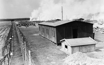 Image shows a small building with barbed wire fencing around it.  It is an image of a concentration camp in Germany.
