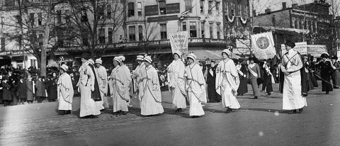 Photo shows women marching with banner "National Woman Suffrage" at the Woman Suffrage Parade