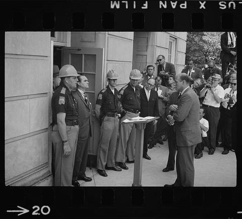 Photograph showing Gov. Wallace standing defiantly at a door while being confronted by Deputy U.S. Attorney General Nicholas Katzenbach.