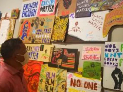 A person looking at a wall filled with signs advocating for civil rights