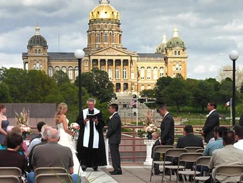 Wedding ceremony on the terrace of the State Historical Building featuring the Iowa State Capitol building in the background