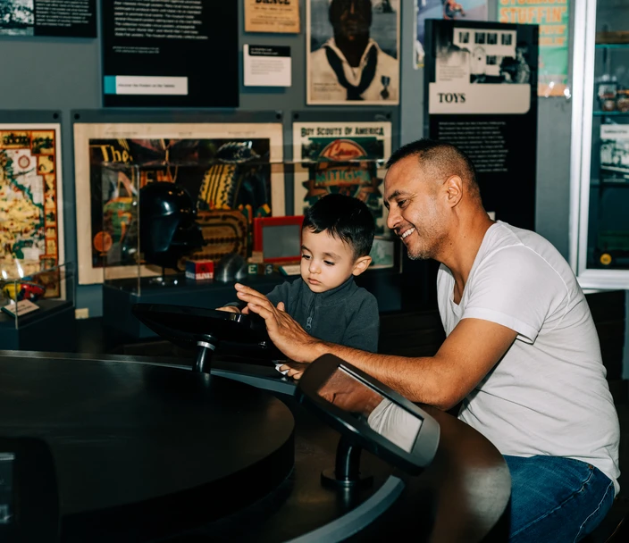 A man and child explore the collection on iPads in the Visible Vault exhibit