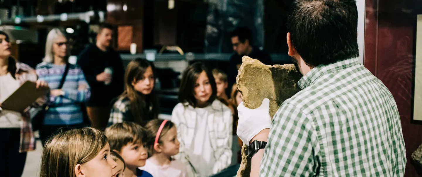 A staff member shares historic artifacts to a group of schoolchildren