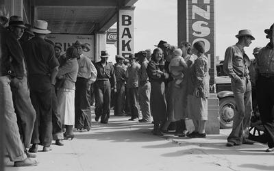 The source is a black and white photograph showing a line of men, women, and children waiting for relief checks in California.