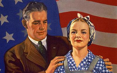 Husband, in suit, and wife in working clothes, standing in front of U.S. flag.