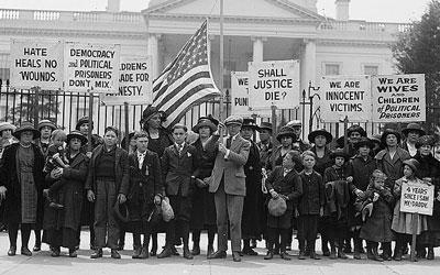 The photo is a black and white image of women and children holding picket signs.  