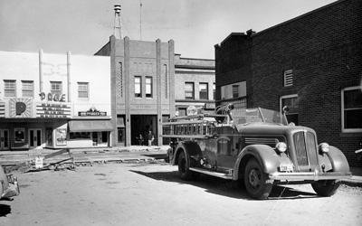 1950s motorized fire truck seen parked in a parking lot with a street construction happening in the background.
