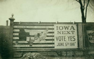 Billboard urging Iowans to vote for women’s suffrage in primary election of June 5, 1916.  Large text says, “Iowa Next.  Vote yes June 5th 1916” and is next to a map of the 48 contiguous states with states where “full suffrage” and “partial suffrage” are indicated.  Iowa is shown as “partial suffrage.”
