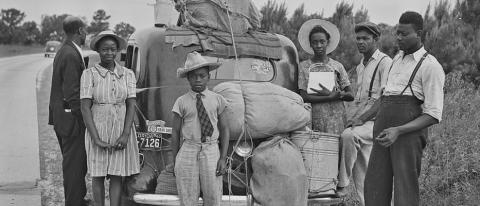 Image of Black migrants standing near their loaded-down car along a road in North Carolina as they travel from Florida to New Jersey to take jobs picking potatoes.