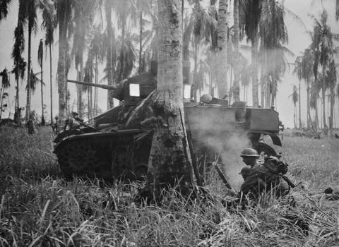 Black and white image of a tank and two soldiers in Buna.