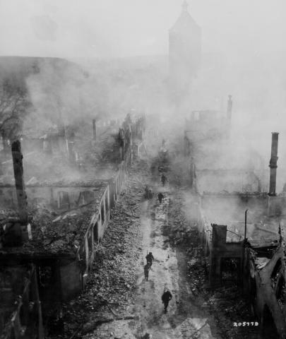 Black and white image of a street with US soldiers that had been bombed in Germany.  