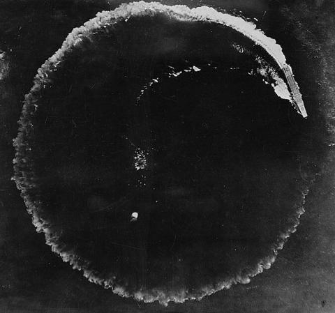 Black and white image of a Japanese battleship circling to avoid a US air attack in the Pacific.