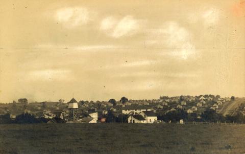 Landscape view of Buxton, Iowa, circa 1910. The photograph shows two water towers, a few two-story buildings, dozens of identical houses, along with streets of the town.