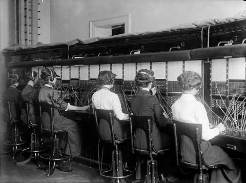This photograph shows six female switchboard operators at work. 