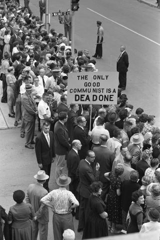 A man holds a anti-communist protest sign as many other Iowans gather to see Soviet Premier Nikita Khrushchev.