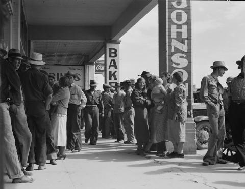 The source is a black and white photograph showing a line of men, women, and children waiting for relief checks in California.