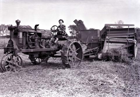 Black and white photo of a female farmer on a tractor.