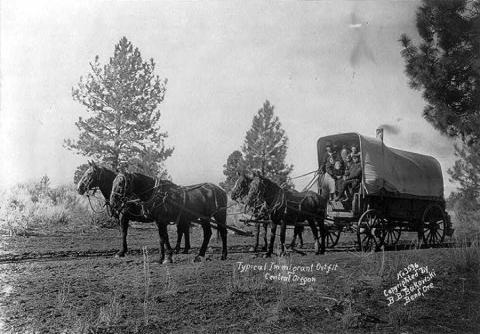 Immigrants in a horse-drawn Conestoga wagon in Central Oregon. 