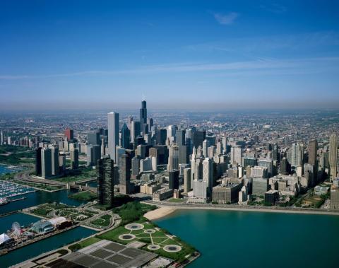Dozens of skyscrapers seen near the shore of Lake Michigan in this photograph of downtown Chicago.  Navy pier visible in the foreground.  Photo is too high up to see any vehicles or pedestrians.