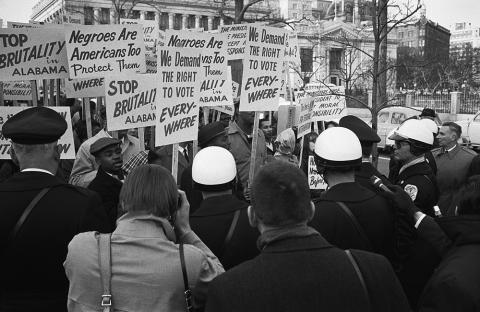 African American demonstrators outside the White House, with signs "We demand the right to vote, everywhere" and signs protesting police brutality against civil rights demonstrators in Selma, Alabama.