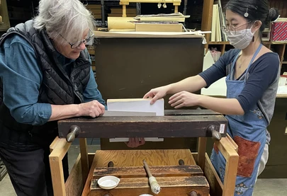 Two people work on repairing a book in the paper conservation lab