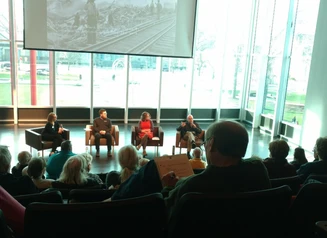 Four people sit and participate in a panel conversation in front of an audience
