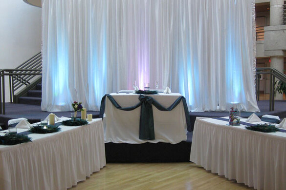 State Historical Building atrium set up for a wedding reception with the couple's table in front of a lighted curtain