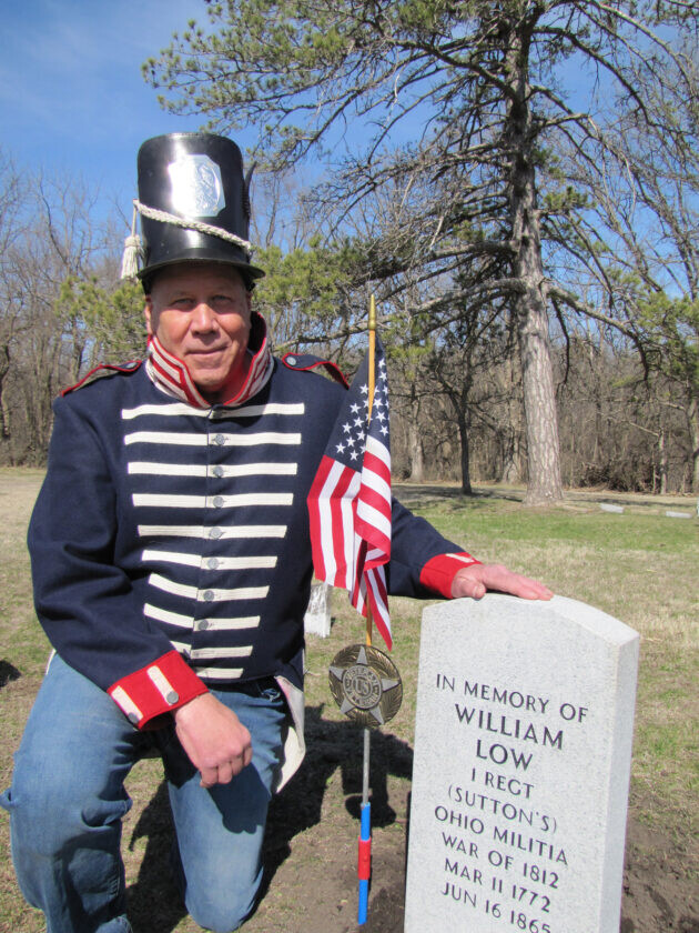Man in war costume next to War of 1812 grave