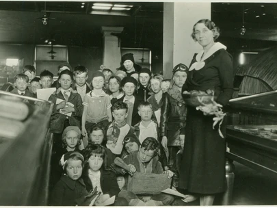 State Historical Society employee Halla Rhode teaching 3rd grade students of Hubbell School in Des Moines on a field trip to the old State Historical Building in Des Moines, Iowa. February 21, 1934.