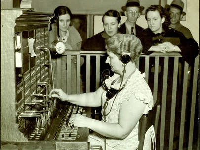 Persons gathered at telephone operator's switchboard awaiting news related to a Mason City bus and train collision. Renwick, Iowa. October 1937. 