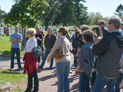 A group of adults listen to a tour at an historic Iowa cemetery